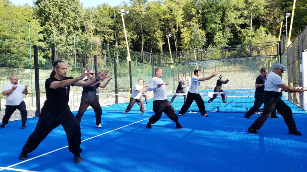 Students practicing qi gong in rows on an outdoor court